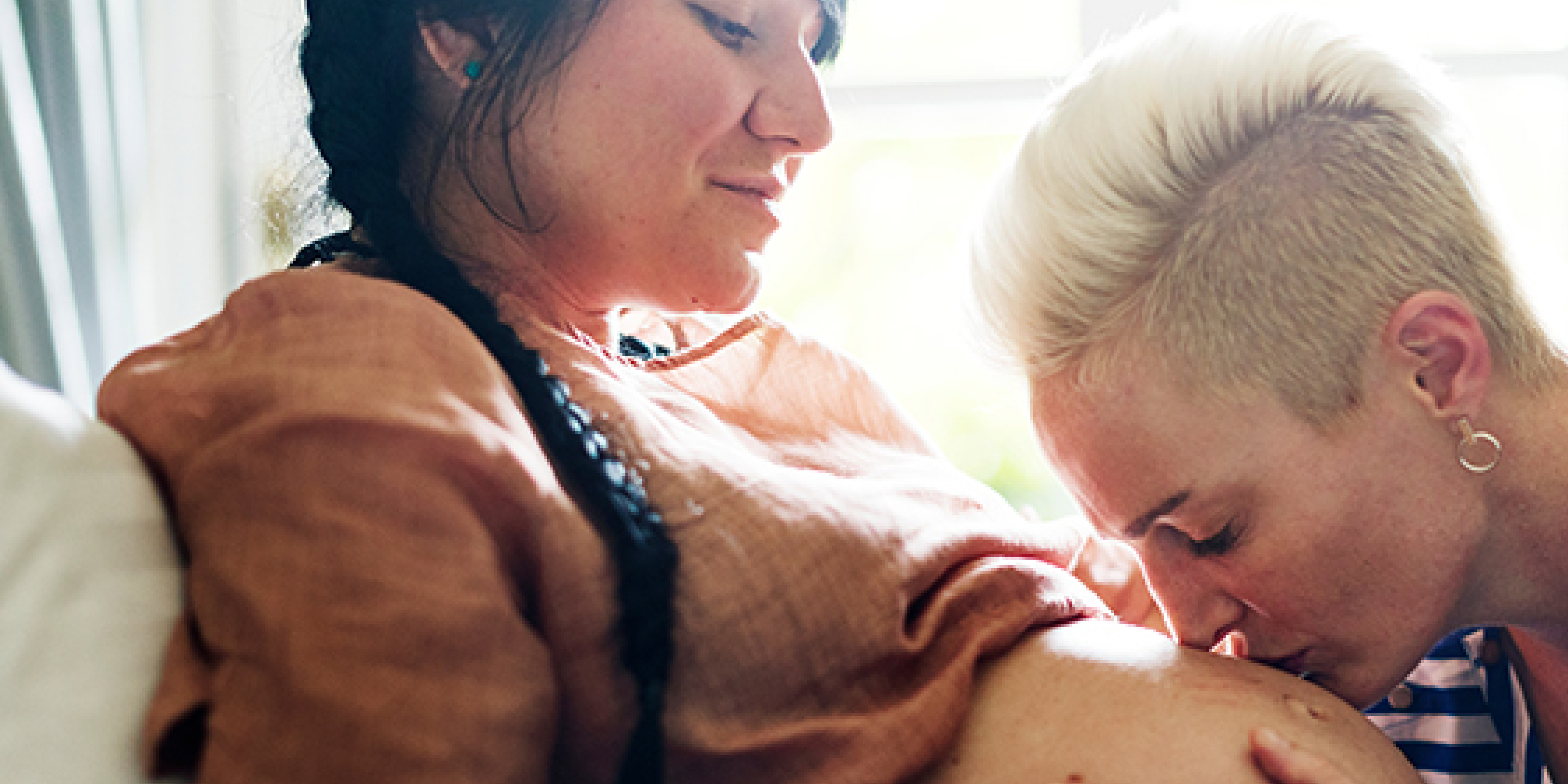 Mother kissing belly of pregnant woman